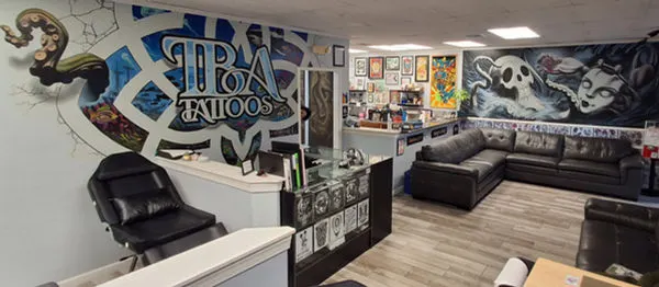 Inside TBA Tattoos in West Palm Beach, showing the TBA mural, flash wall and studio seating