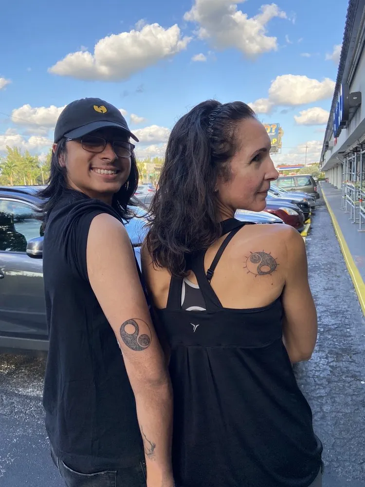 Two clients outside TBA Tattoos in West Palm Beach showing their new small tattoos