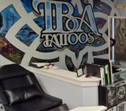 Inside TBA Tattoos: the shop mural with the TBA Tattoos lettering painted behind the front counter